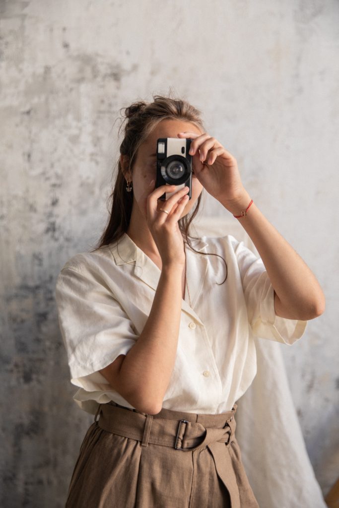 Woman posing with a camera. 
"How to Plan The Perfect Branding Photoshoot" 