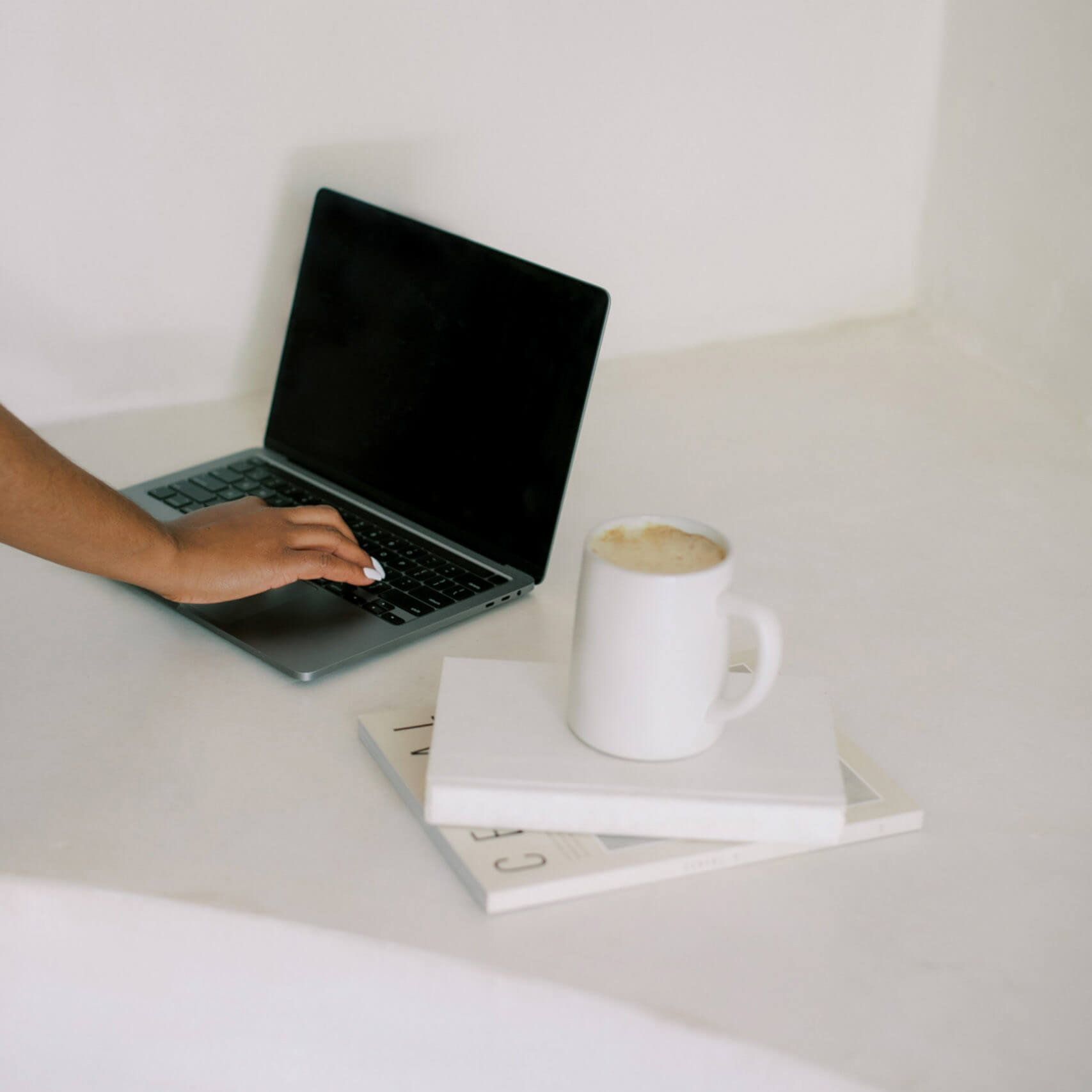 Black woman using an iPad in a minimal space with coffee cup