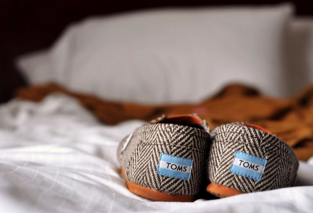 A pair of TOMS shoes on a bed